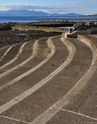 Looking out from Ardrossan Sea front
Watching the Arran ferry approach the harbour at Ardrossan.  The steps are part of what used to be an outdoor swimming pool filled with rather cold tidal sea water.  It has long since fallen into dis-repair. Many of the coastal towns had such structures, summers must have been warmer then. [url=http://www.streetmap.co.uk/map.srf?X=224155&Y=641290&A=Y&Z=115/] Map location. [/url]

