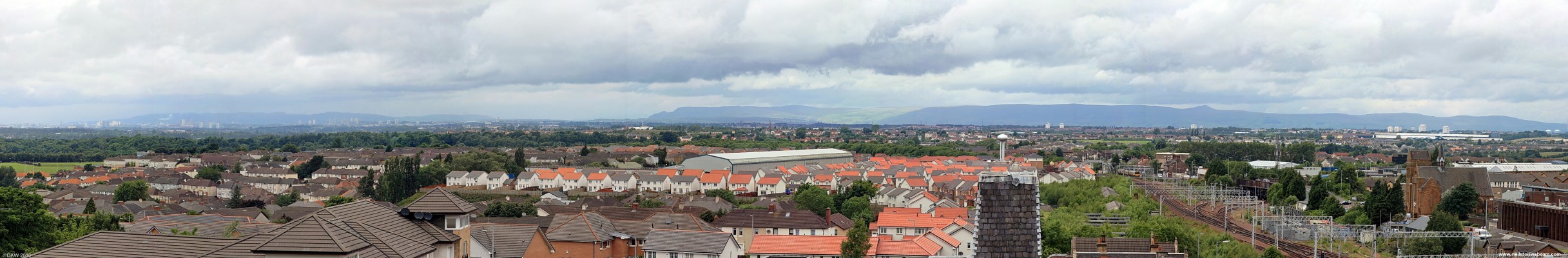 Panoramic view over Motherwell
Taken from the top of the Motherwell Heritage Centre in 2008.  On the left hand side and all along the horizon Glasgow can be seen in the distance.  The centre is dominated by the Motherwell Bridge Engineering factory with its iconic water tower.  The factory once covered all the area where the red tiled houses now stand.  On the right you can see Coatbridge in the sitance and on the extreme right are the two LNG storage tanks at Glen Mavis. 
